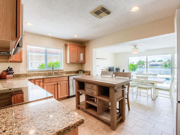 Kitchen with stone counters and island opening to a bay-facing dining area